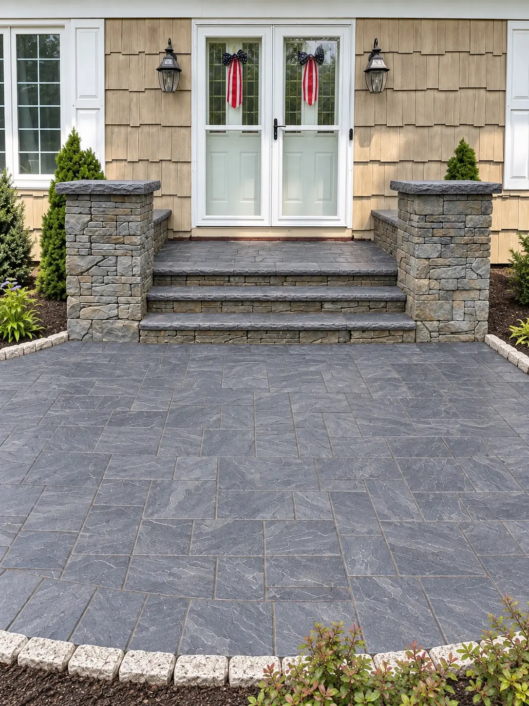 Symmetrical stone entrance steps and piers opening onto a gray paver landing