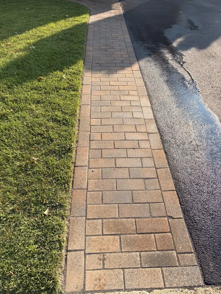Freshly washed paver walkway beside a driveway